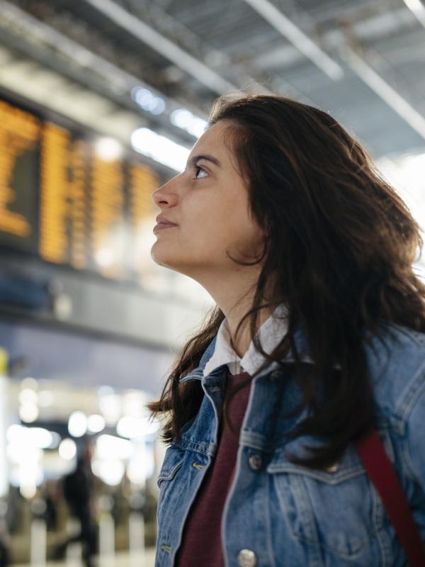 Frau prüft eine Abfahrtentabelle am Bahnhof