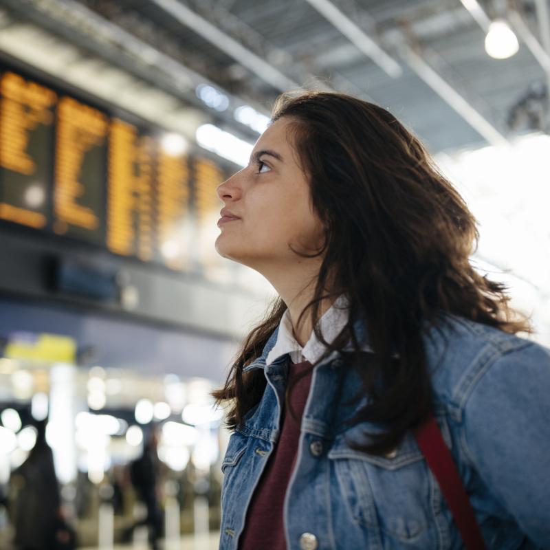 Frau prüft eine Abfahrtentabelle am Bahnhof