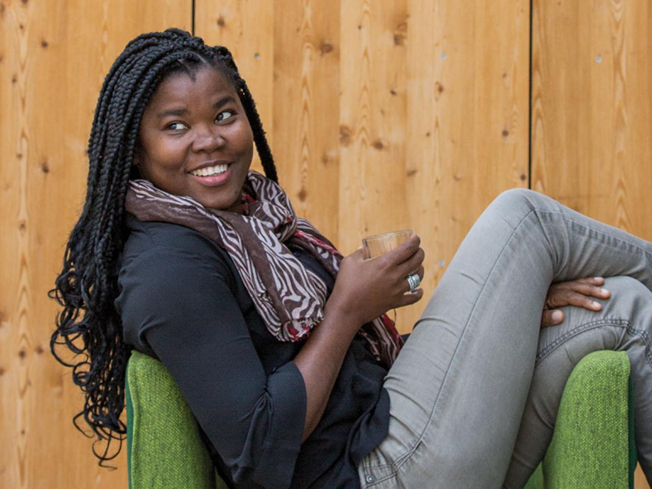 Karen Mbomozomo sitzt locker auf einem Stuhl