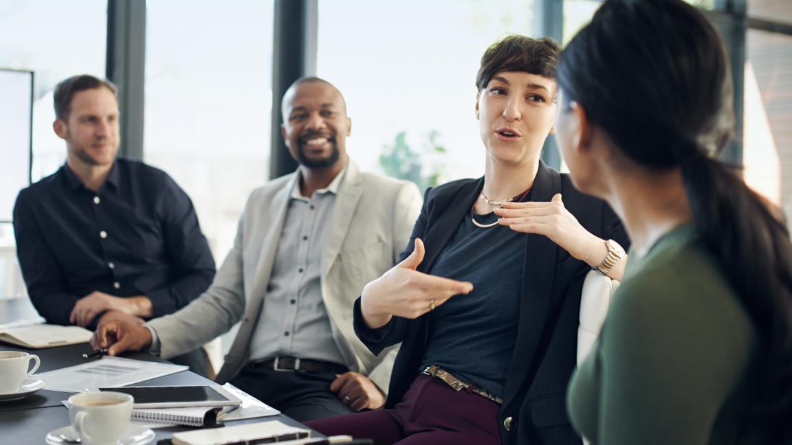 Frau im Meeting erklärt Mitarbeitern etwas